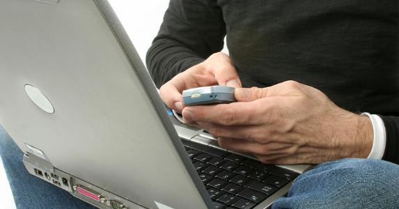 man-using-old-smartphone-and-laptop_573x300